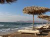 Ein Strand mit Strandliegen und Sonnenschirmen aus Schilf