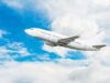 Ein weißes Flugzeug in der Luft mit blauem Himmel und Wolken