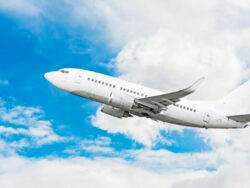 Weißes Flugzeug in der Luft mit Wolken und blauen Himmel im Hintergrund