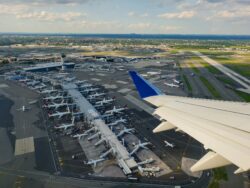 Flugzeugflügel aus Flugzeug fotografiert mit Flughafen im Hintergrund